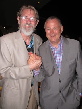 Two elderly men standing close together and smiling at the camera. They are shaking hands. Both are wearing suits; the man on the left has a beard and glasses and is wearing a light-colored suit, while the man on the right, resembling one of California's Senators, is in a checkered shirt and gray suit. CA Norml