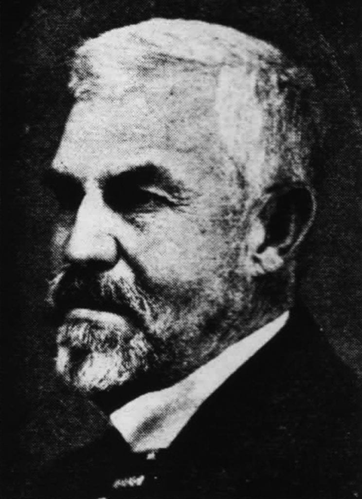 Black and white side profile portrait of an older man with short, white hair and a full beard and mustache. The man is wearing a dark suit and a bow tie. The background is dark, emphasizing his facial features and formal attire, reminiscent of California's dignitaries who saw the 100-year-old ban on marijuana. CA Norml