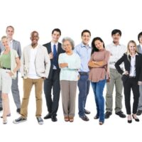 A diverse group of thirteen people of different ages and ethnicities stand against a white background. They are dressed in various casual and professional clothing styles, with neutral or smiling expressions. Among them are members advocating for employment rights, conveying a sense of community and inclusiveness. CA Norml