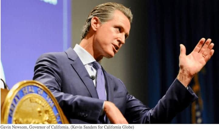 A man in a suit gestures with his right hand while speaking at a podium. The podium displays a gold seal. A purple screen is visible in the background, and he discusses California's National Guard efforts. CA Norml