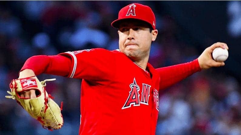 A baseball player wearing a red jersey and cap with an "A" logo is pitching. His arm is extended mid-throw, and he holds a baseball in his hand. The background is blurred, focusing on the pitcher, creating a compelling image for Overdose Awareness Day to highlight the importance of addressing opiate use. CA Norml