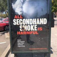 A bus stop advertisement shows large text reading, "ALL SECONDHAND SMOKE IS HARMFUL," with "HARMFUL" in red. Below, smaller text lists "Vape Hazards, Marijuana, Cigarillos, Hookah, Cigarettes." The background features smoke, and the website "SecondhandDangers.org" appears at the bottom. CA Norml