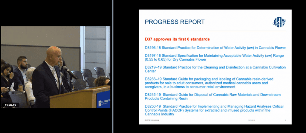 A man in a suit speaks at a podium in a conference room while a presentation slide titled "Progress Report" is displayed. The slide lists several ASTM standards related to CBD and cannabis, including water activity determination, cleaning, packaging, and HACCP systems. CA Norml
