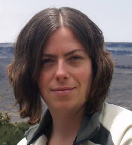 A person with shoulder-length brown hair and wearing a light jacket is looking at the camera. The background features a rugged, rocky landscape under an overcast sky, reminiscent of the scenes from California NORML's June 2021 event. CA Norml