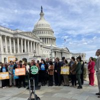 A diverse group gathers in front of the U.S. Capitol building for Lobby Day, holding signs supporting cannabis legalization and Latino representation, during an outdoor press event organized by the Cannabis Unity Coalition on a sunny day. Ca NORML